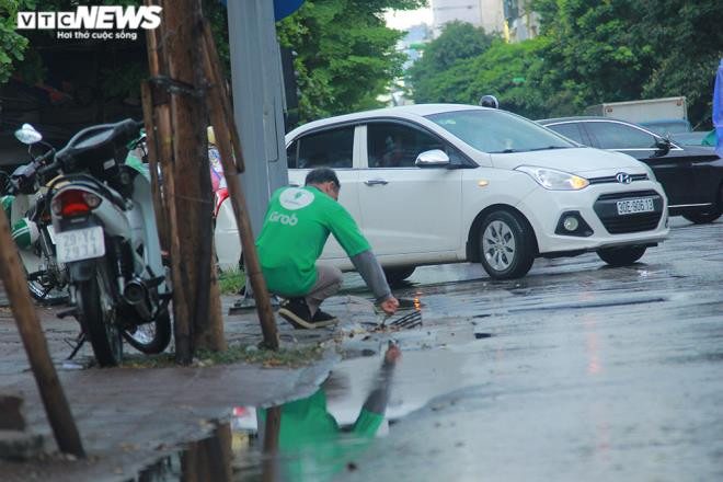 Tài xế xe ôm khơi thông cống thoát nước trên phố Hà Nội sau trận mưa lớn - 4