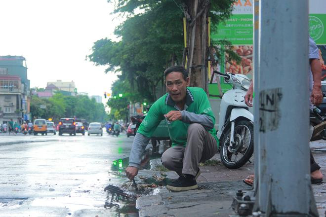 Tài xế xe ôm khơi thông cống thoát nước trên phố Hà Nội sau trận mưa lớn - 5