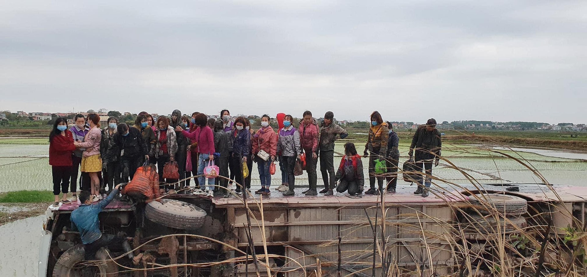 Xe chở hàng chục công nhân gặp tai nạn, lật ngang giữa ruộng - Ảnh 1. Xe chở hàng chục công nhân gặp tai nạn, lật ngang giữa ruộng - Ảnh 1.