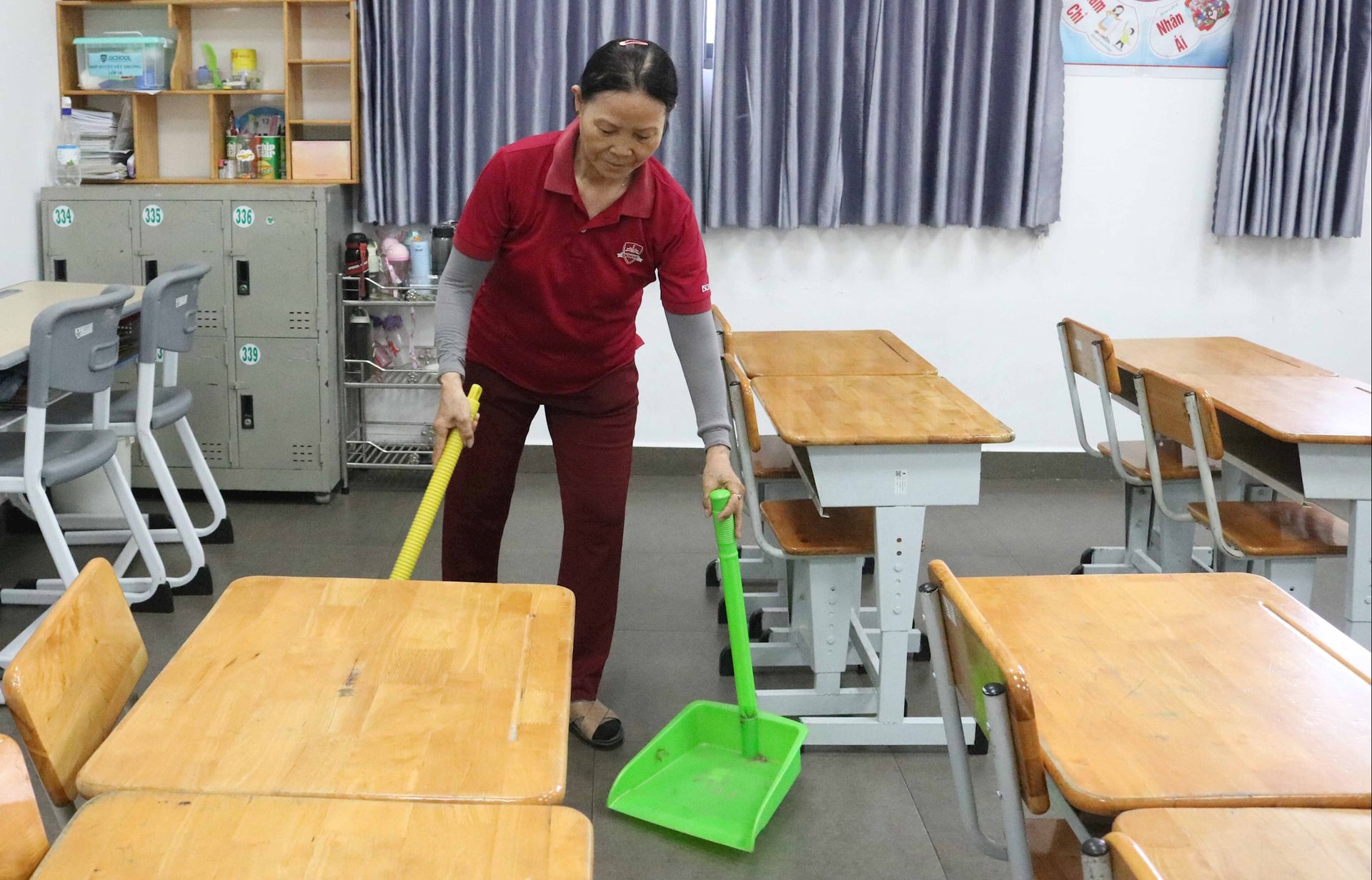 Nhân viên tạp vụ đang lau dọn lớp học trước khi học sinh đến trường