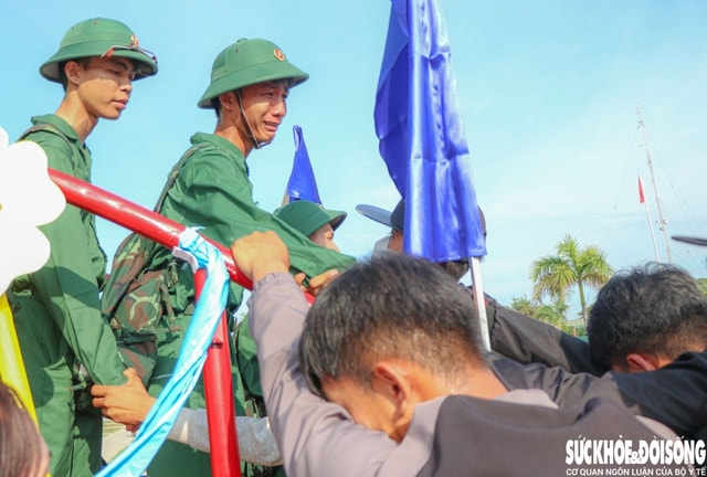 Giữa nắng sớm rực rỡ, người tân binh không nén được xúc động nắm chặt tay người thân qua lan can cầu vinh quang, bịn rịn chia tay người thân lên đường nhập ngũ, mang theo lời dặn dò, niềm tin yêu và cả những ước hẹn ngày trở về. Ảnh: Duy Ngọc.