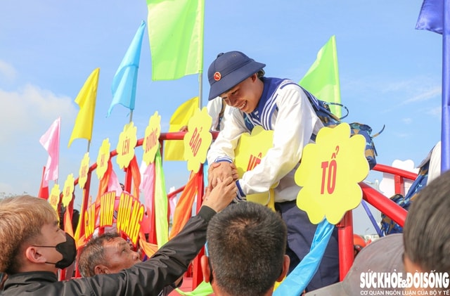 Một tân binh tranh thủ cúi xuống nắm tay người thân, gửi lại nụ cười tươi như lời hứa sẽ hoàn thành tốt nhiệm vụ. Ảnh: Duy Ngọc.
