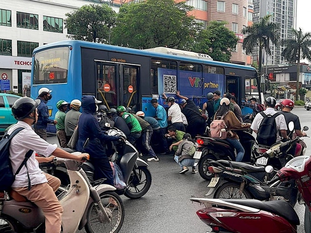 Cận cảnh người dân nâng xe buýt cứu tài xế mắc kẹt - Ảnh 2.