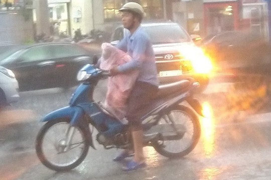 Nghẹn ngào khoảnh khắc ông bố trùm kín áo mưa cho con còn mình thì ướt sũng