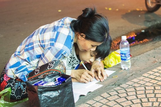 Hình ảnh người mẹ nghèo cầm chặt tay con uốn nắn từng nét chữ trên vỉa hè gây xúc động