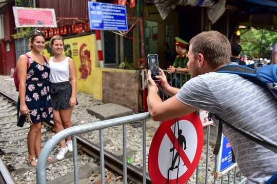 Ảnh: Du khách xếp hàng chụp ảnh phố cà phê đường tàu qua rào chắn sau 2 tuần đóng cửa