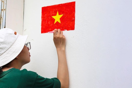 Người trẻ vẽ cờ Tổ quốc trên mái nhà, trước cổng