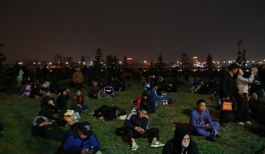 Người dân ngồi, nằm ở bãi cỏ chờ vào đền Trần Nam Định dâng lễ, xin lộc ấn