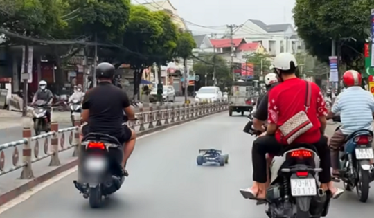 Phạt thanh niên vừa đi xe máy vừa điều khiển ô tô mô hình trên phố